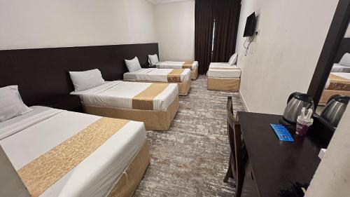 a hotel room with three beds and a desk at فندق سرايا سيف مكة المحبس in Makkah