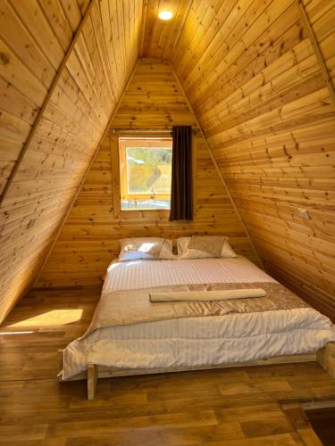 Bett in einer Holzhütte mit Fenster in der Unterkunft Nature Forest Cabins in Gerasa