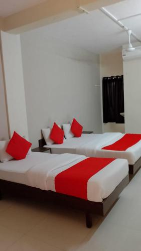 two beds in a room with red and white at Hotel Nawanagar Residency in Jamnagar