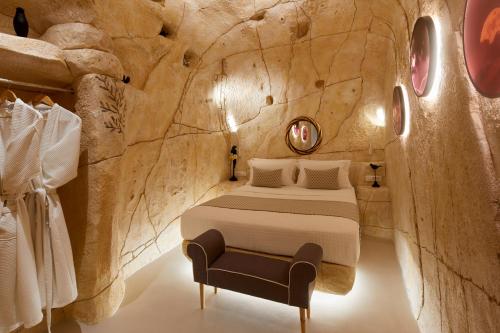 ein Schlafzimmer in einer Höhle mit einem Bett und einem Stuhl in der Unterkunft Artion Luxe Apartment in Vourvoúlos
