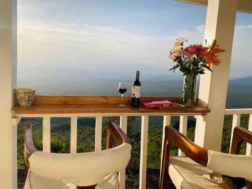 a balcony with a table with a glass of wine and flowers at harmonious two bed cottage with breathtaking views in Kajiado