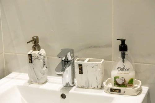 a bathroom sink with two bottles of soap and a mirror at Avery 2 Studio @Embassy Gardens in Accra