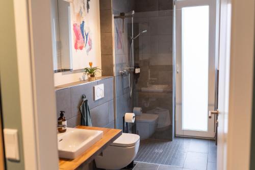 a bathroom with a sink and a toilet and a shower at Familiensuite BoHo am See - Netflix - Grill - Parken in Möhnesee