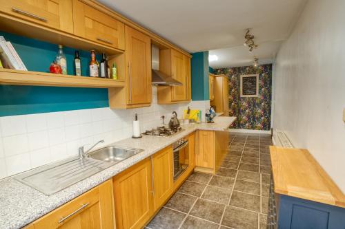 a kitchen with wooden cabinets and a sink at Pass the Keys 2 Bed Flat in Old School House in Lincoln