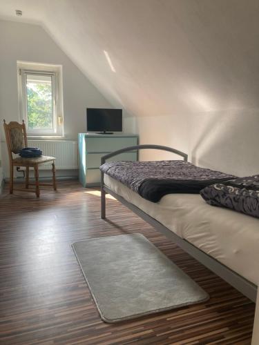 1 dormitorio con 2 camas, TV y silla en Gästehaus Lauerwald, en Niesky