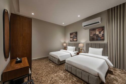 a hotel room with two beds and a television at شقق ممسى المخدومة in Riyadh