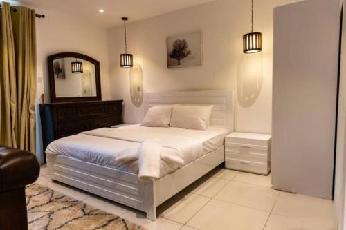- une chambre avec un lit blanc et un miroir dans l'établissement Big Beautiful Suite @ Embassy Gardens, Cantonments, à Cantonments