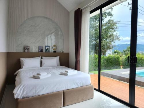 een slaapkamer met een groot bed en een groot raam bij กอลมาร์ พูลวิลล่า เขาใหญ่ in Pong Talong
