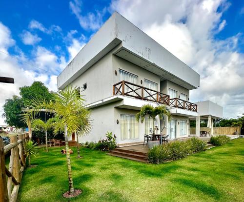 a large white house with a grass yard at Shaqat Barra Flat in Barra Grande