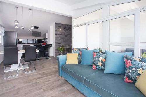 sala de estar con sofá azul y cocina en Apartman Luis Light, en Kaštela