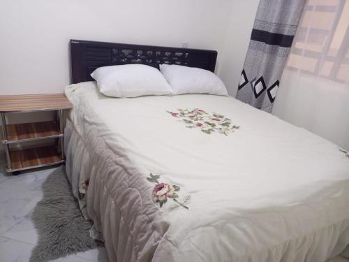 uma cama com um cobertor branco com flores em Kozi Luxury Apartment in Kisumu em Kisumu