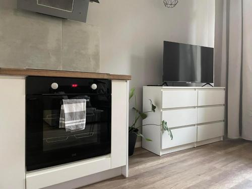uma cozinha com um forno, uma televisão e uma cómoda em La Mia Casa Apartament Świdnica em Świdnica
