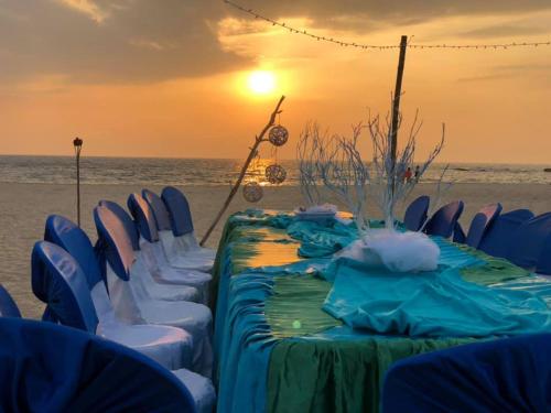 a table and chairs on the beach with the sunset at Sea Crest Beach Villa in Ambalangoda