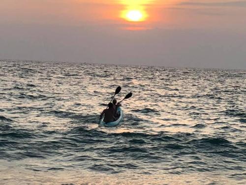 a person in a kayak in the ocean at sunset at Sea Crest Beach Villa in Ambalangoda