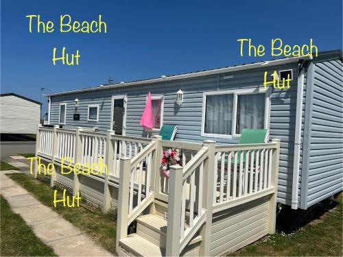 a mobile home with a porch and a white fence at Lyons Robin Hood, RHYL "The Beach Hut" in Rhyl