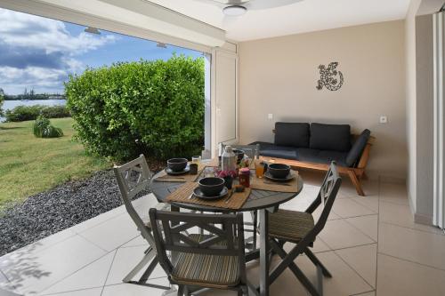 a patio with a table and chairs and a couch at Refait à neuf, magnifique vue sur le lagon appartement 4 à 5p in Marigot