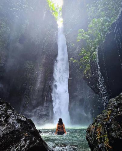 a woman in the water in front of a waterfall at Munduk Kupang Sekumpul Villa in Singaraja
