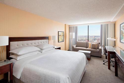 a hotel room with a large white bed and a desk at Sheraton West Des Moines in West Des Moines