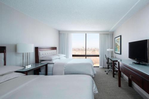 a hotel room with two beds and a flat screen tv at Sheraton West Des Moines in West Des Moines