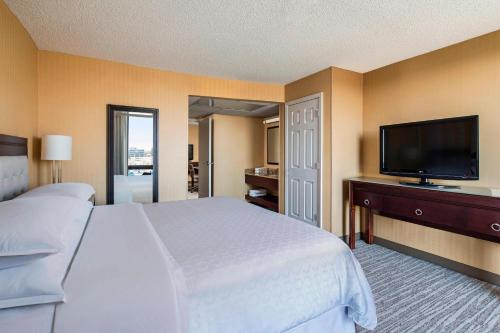 a bedroom with a large bed and a flat screen tv at Sheraton West Des Moines in West Des Moines