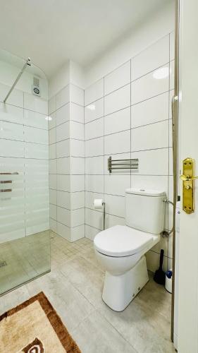 a bathroom with a toilet and a glass shower at Sunset apart, large terrace, pool, Best location! in Puerto de Santiago