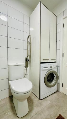 a bathroom with a toilet and a washing machine at Sunset apart, large terrace, pool, Best location! in Puerto de Santiago