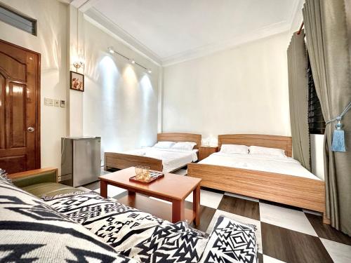 a room with two beds and a table at BÊ TÔNG RESIDENCES HOMESTAY in Can Tho