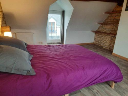 uma grande cama roxa num quarto com uma escada em Maison de ville em Déols