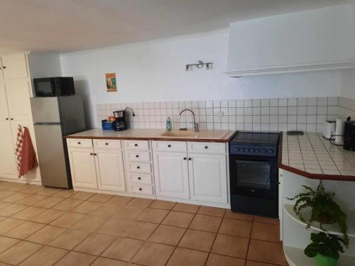 uma cozinha com armários brancos e um fogão preto em Maison de ville em Déols