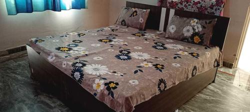 Una cama con una manta con flores. en SPOT ON Hotel Golden Gajraula, en Gajraula
