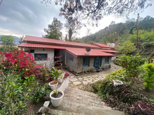 een klein huis met een rood dak en wat bloemen bij The Vergomont - A heritage homestay near Nainital in Nainital