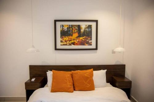 a bed with orange pillows and a picture on the wall at Cantonments Beautiful 2 Bedroom Apartment in Cantonments