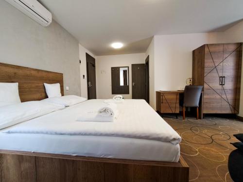 a bedroom with a large white bed and a desk at Wellness Hotel Vinnay in Vinné