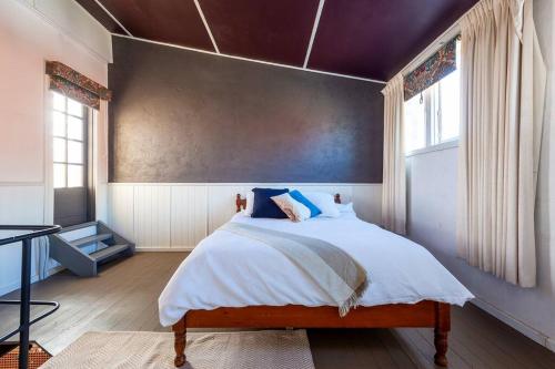 1 dormitorio con 1 cama grande con sábanas blancas y almohadas azules en Historical Building dating back to 1900 en Nhill
