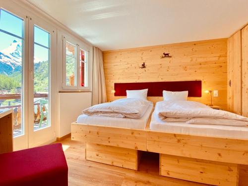 Un dormitorio con una cama con una pared de madera. en Hotel Capricorn, en Zermatt