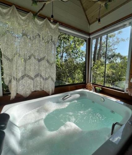 a large bath tub in a room with windows at Cabana Mirim Estalagem Rural in Gramado