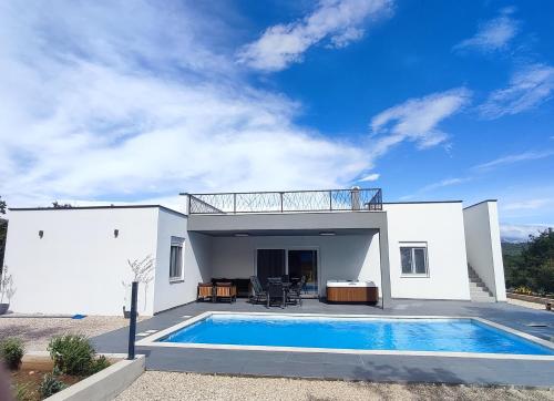 a white house with a swimming pool in front of it at Villa Tempest with Private Pool and Jacuzzi in Slivnica