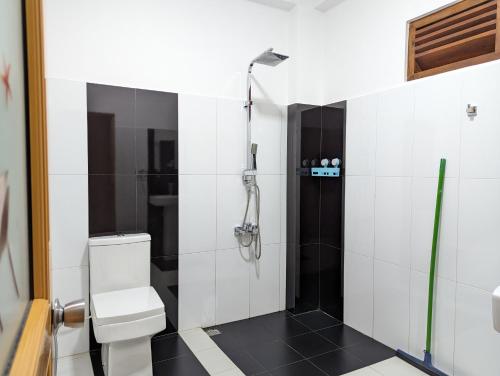 a white bathroom with a shower and a toilet at Nilowin Glenanore Guesthouse in Haputale
