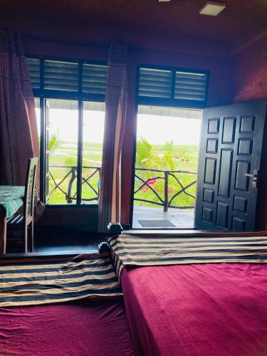 a bedroom with a bed and a door and a window at Bundala Flamingo Cotteges in Hambantota
