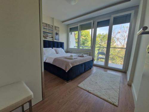 a bedroom with a bed and a large window at Royal apartment Sava river Blok 70 in Ada Ciganlija