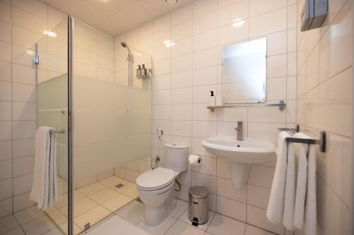 a white bathroom with a toilet and a sink at Riggae Tower Hotel in Kuwait