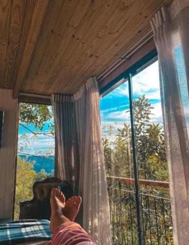 a person laying on a bed in front of a window at Cabana Mirim Estalagem Rural in Gramado