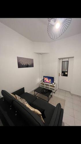 een woonkamer met een bank en een tv bij Appartement centre ville de Saint Quentin in Saint-Quentin