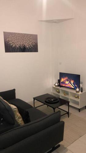 een woonkamer met een bank, een tafel en een tv bij Appartement centre ville de Saint Quentin in Saint-Quentin