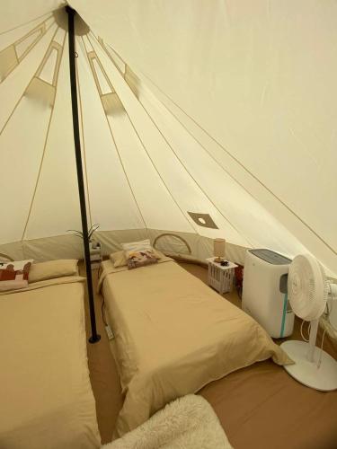a tent with two beds and a fan in a room at The Backyard Glamp - Book The Entire Campground 