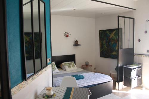 um pequeno quarto com uma cama e um espelho em L'instant Détente 34 em Saint-Aunès