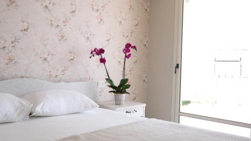 a bedroom with a bed with a vase with flowers on it at Gardenia in ‘Ein el Asad