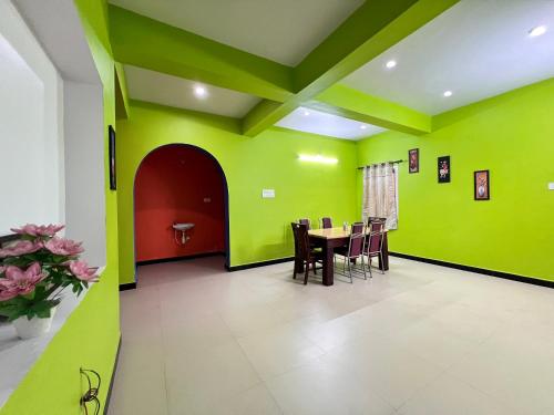 une salle à manger avec des murs verts, une table et des chaises dans l'établissement Golden View Cottage Ooty, à Ooty