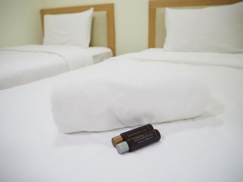 a bottle of lipstick sitting on a white bed at NANA BEST INN HOTEL in Makkasan
