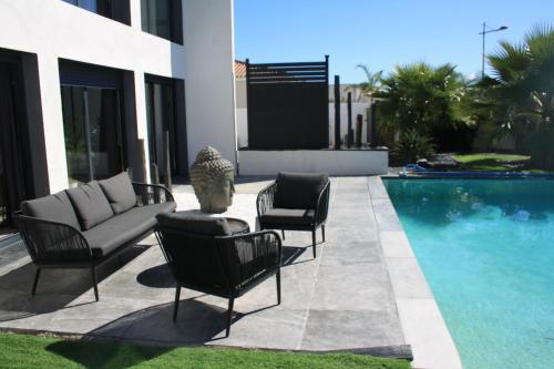 - une terrasse avec 2 chaises et un canapé à côté de la piscine dans l'établissement L'instant Détente 34, à Saint-Aunès